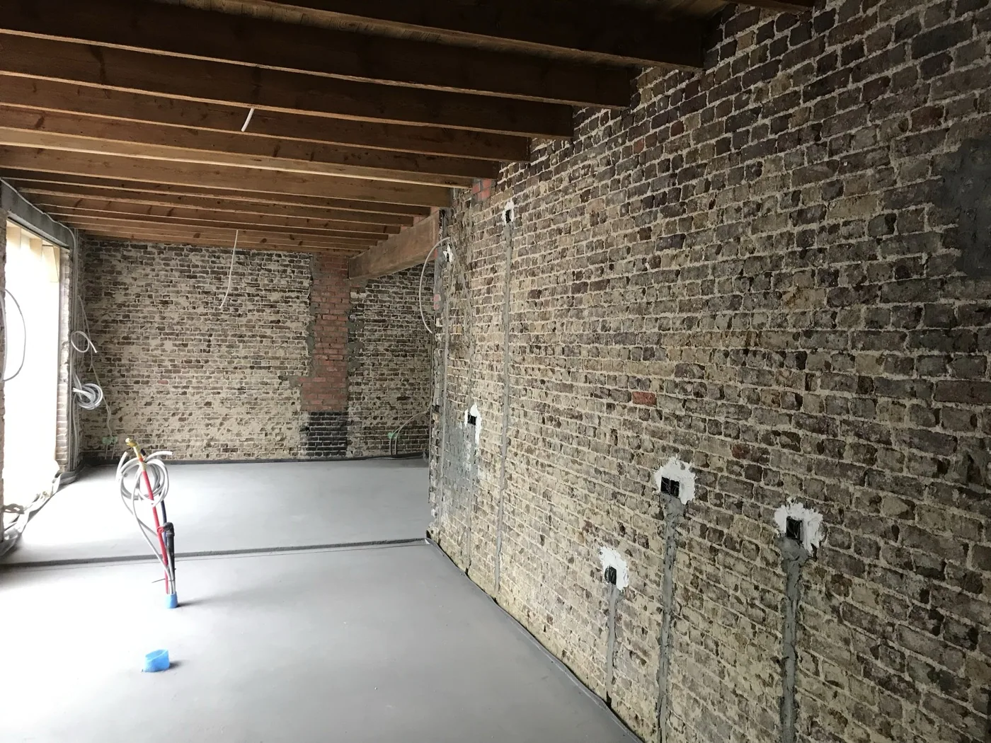 Binnenmuren van natuursteen en baksteen gereinigd, met houten balken aan het plafond