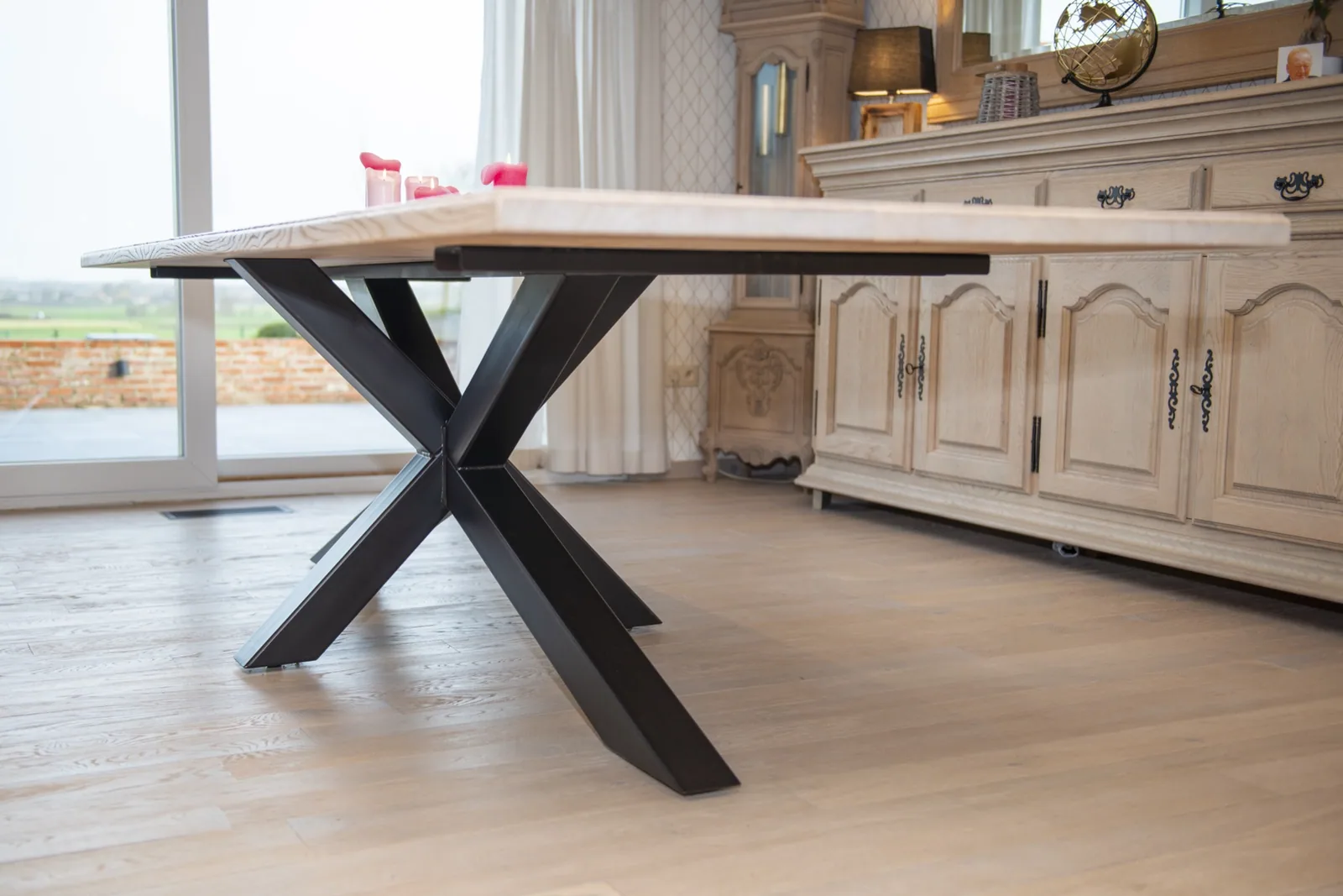 Gestraalde eiken kast en eettafel met kruispoot in een lichte woonkamer