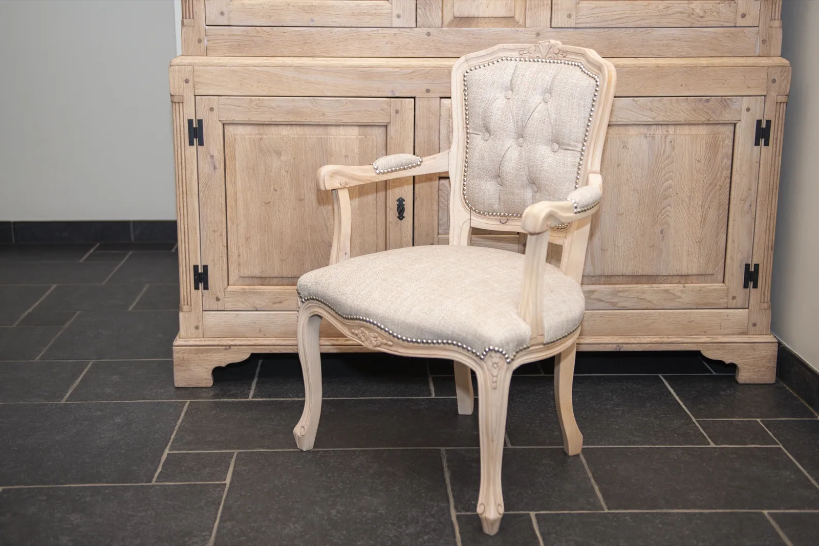 Gestraalde eiken kast met een witte gecapitonneerde fauteuil