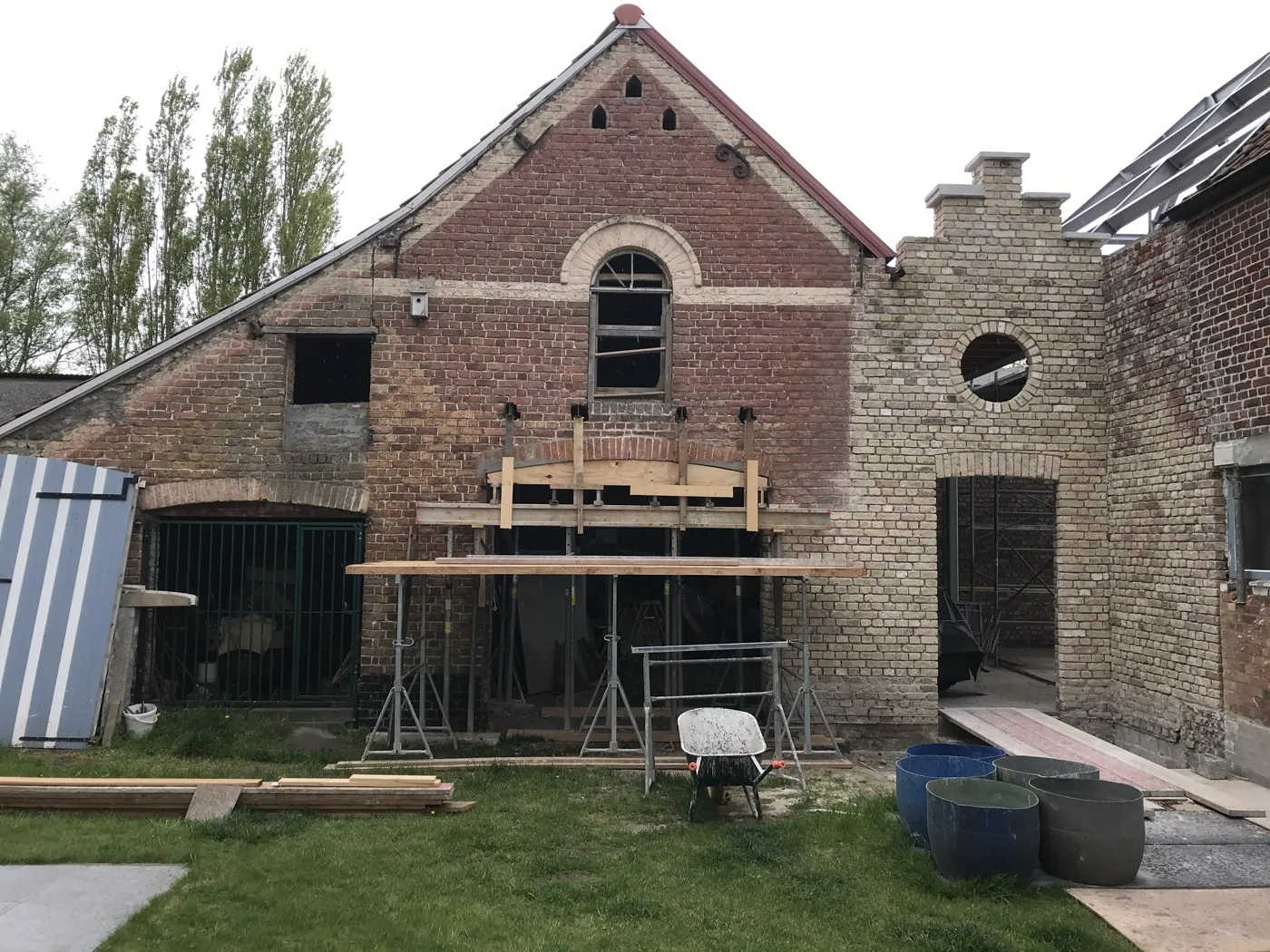 Bakstenen hoevegevel met steiger tijdens het zandstralen