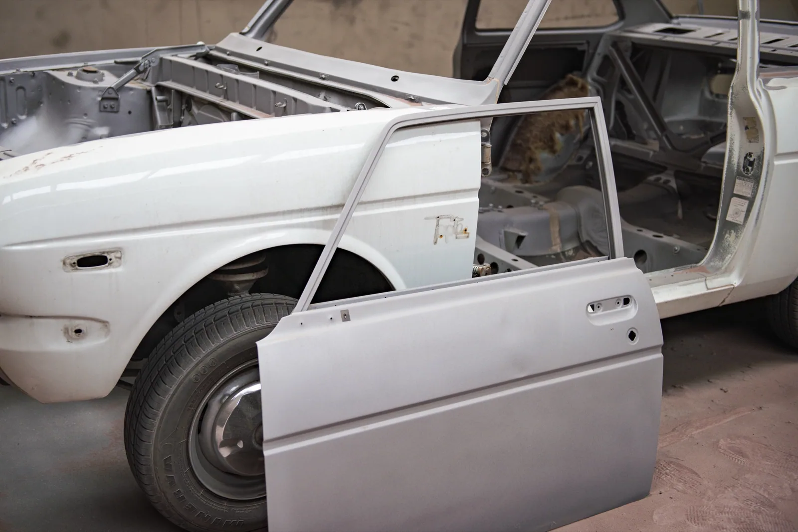 Witte oldtimer met geopende deur, carrosserie gestraald tot op het blanke metaal