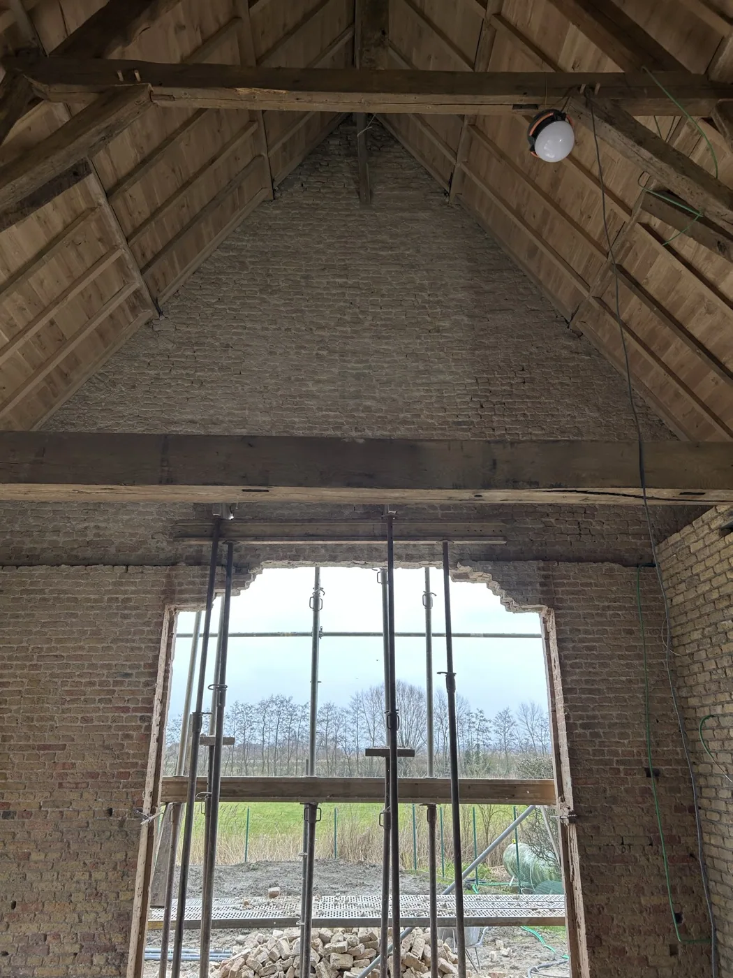 Interieur van een gerenoveerde schuur met gereinigde balken en boogramen